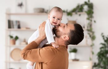 Father holding and kissing his baby.