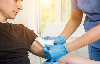 nurse dressing wound for patients hand with burn injury