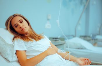 Patient Resting in Hospital Bed with IV Cannula in her Hand. Anemic woman feeling sick from iron deficiency
