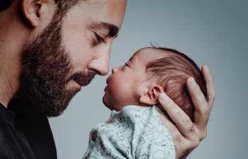 portrait of man looking at his newborn son with loving expression